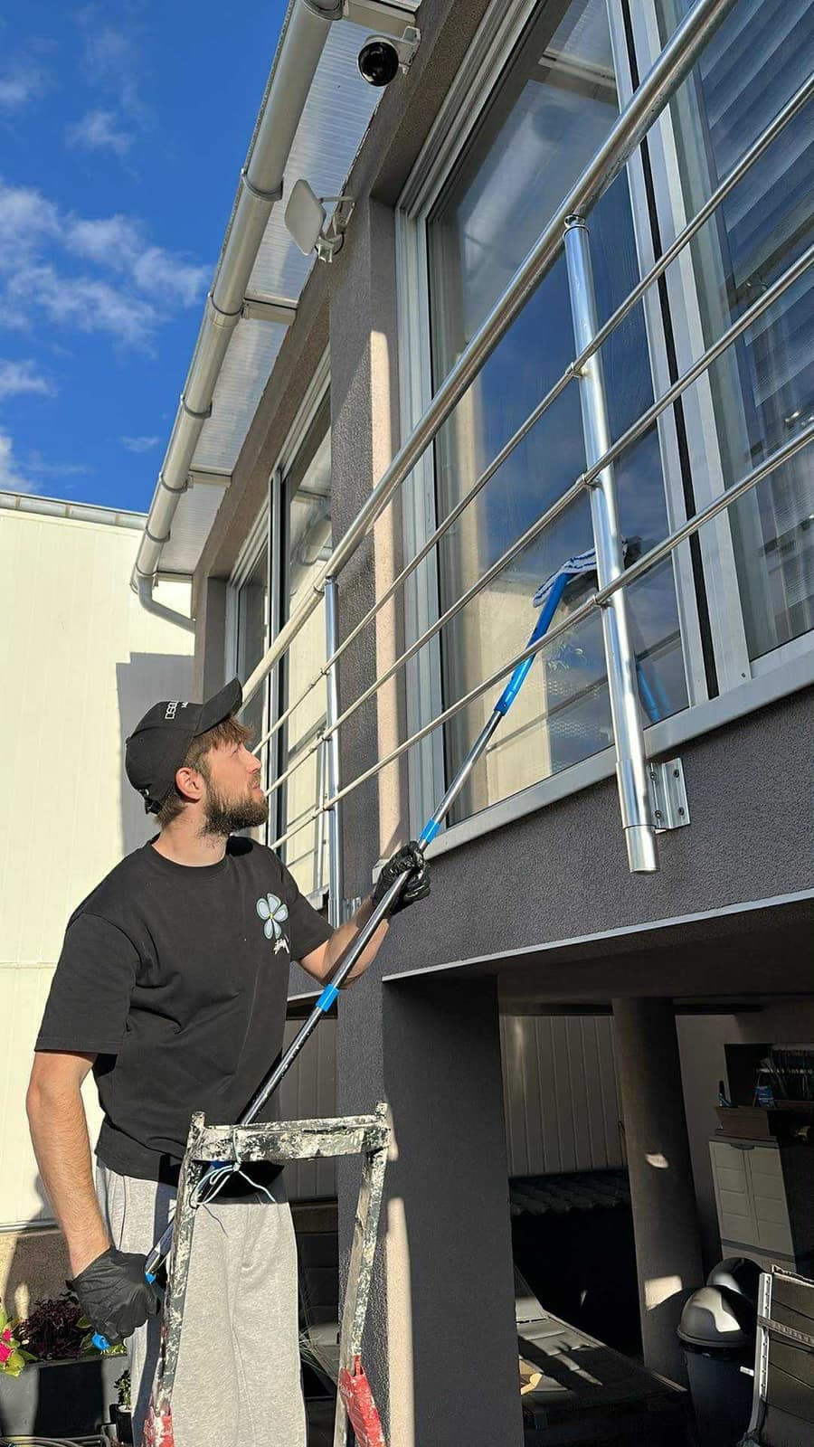 Intervenant Kireya nettoyant les vitres d'une façade à la perche télescopique